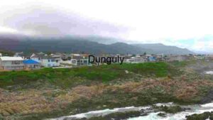 Coastal Town with Rocky Shoreline and Mountain Backdrop