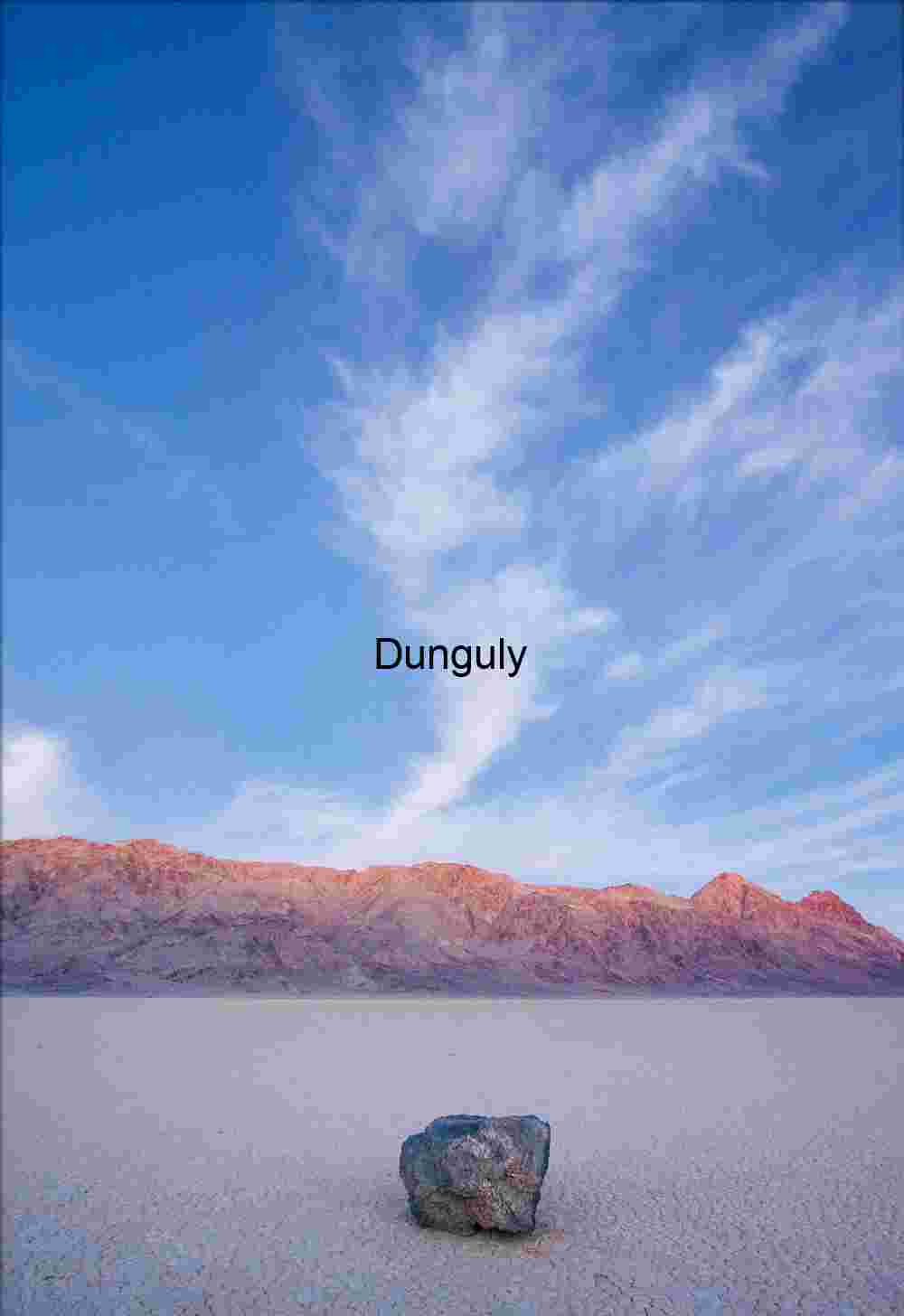 Lonely rock, moving rocks of Racetrack Valley Circular Tracks Leading to a Distant Object Amidst Rugged Mountains