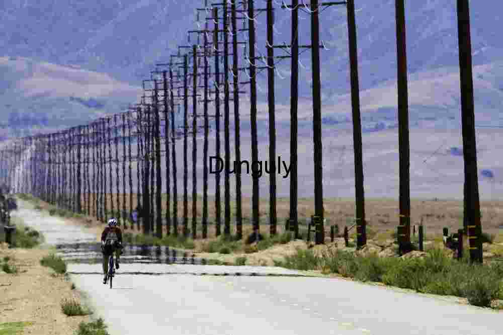 Power poles and heat-haze Cyclist on Desert Road Beneath Power Lines and Mirage