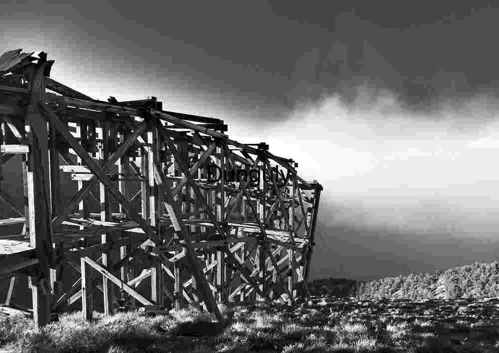 Salt tram summit station about to be engulfed by sandstorm, Inyo Mountains Weathered Wooden Framework in Open Landscape – Industrial Ruin Meets Nature
