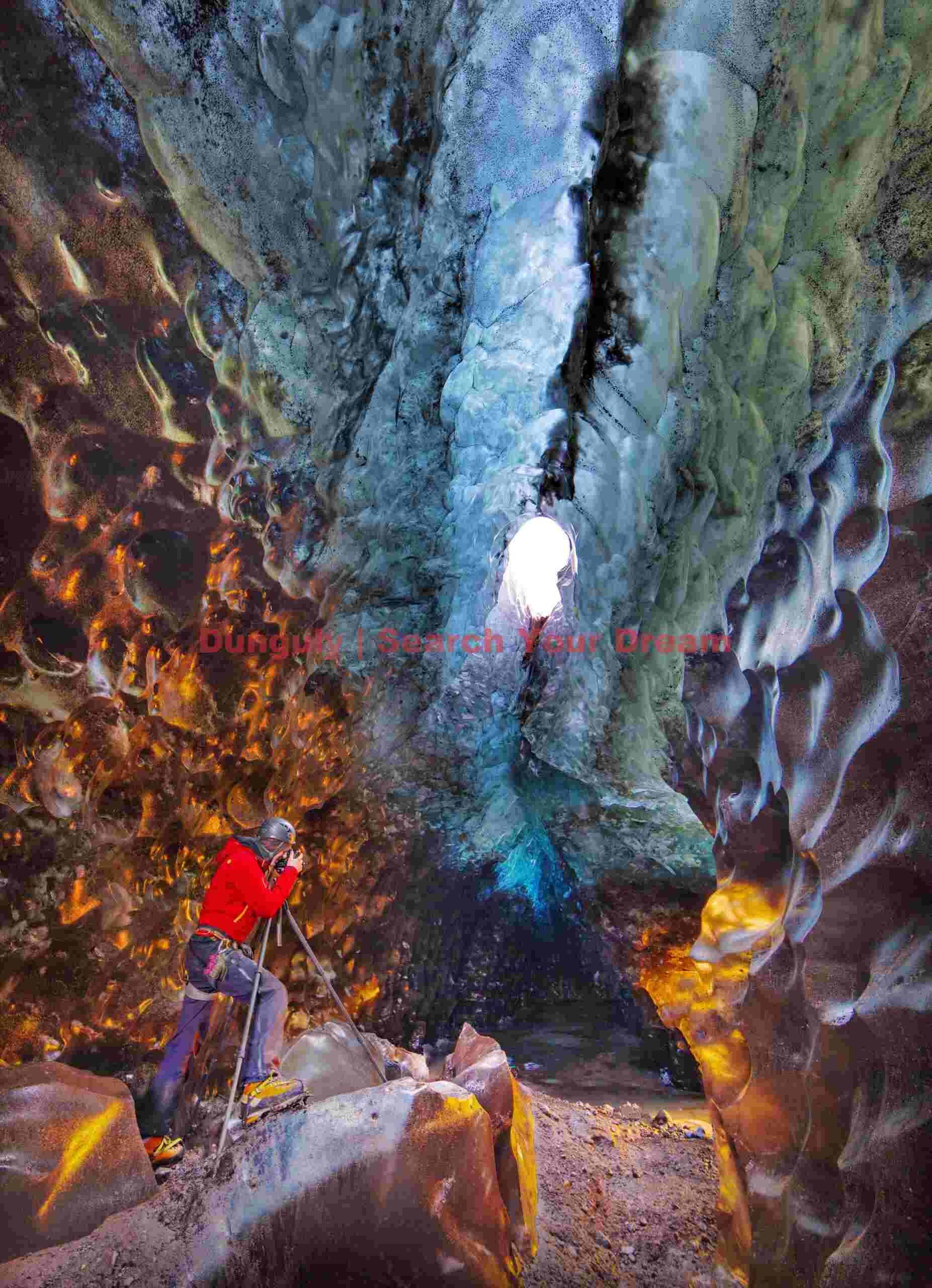 Golden ice cave with photographer in red, Vatnajokull, Iceland Glacial Ice Formation at Golden ice cave with photographer in red, Vatnajokull, Iceland