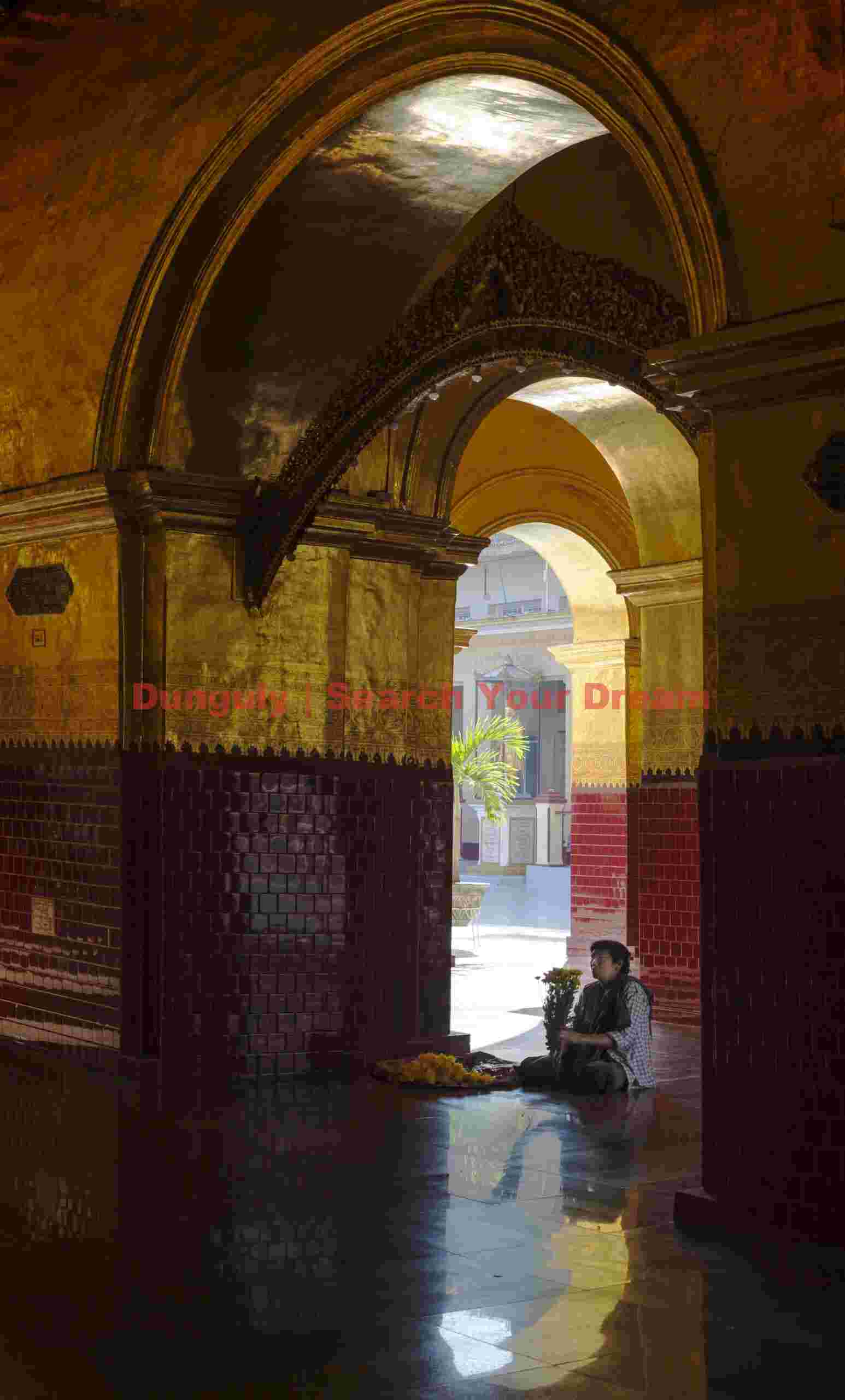 Worshiper with flowers sitting in archway; Burma Worshiper with flowers sitting in archway