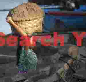 Young girl carrying heavy sand basket among boats