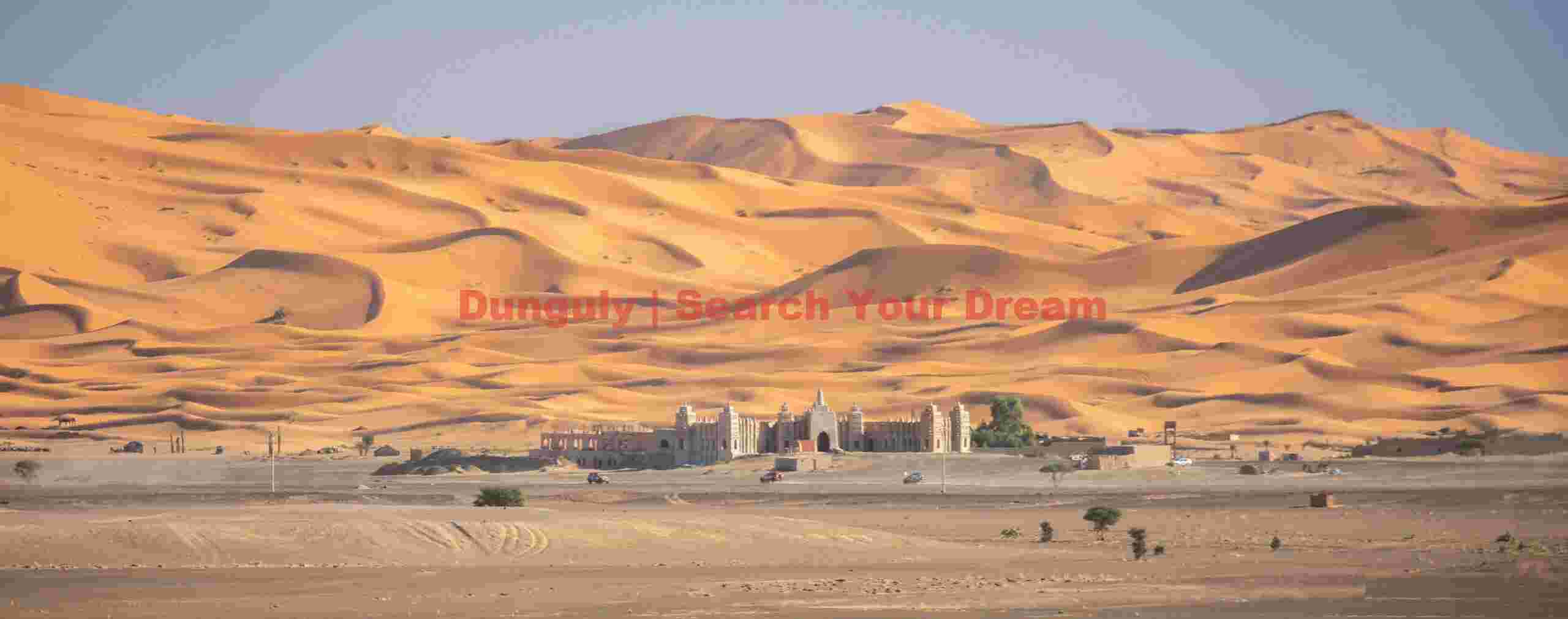 Distant white building below Sahara dunes; Morocco Distant white building below Sahara dunes