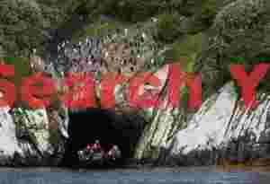 Zodiac emerging from cave below snares penguin colony