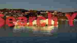 At Home golden hour glow iceberg drifts past greenlandic village