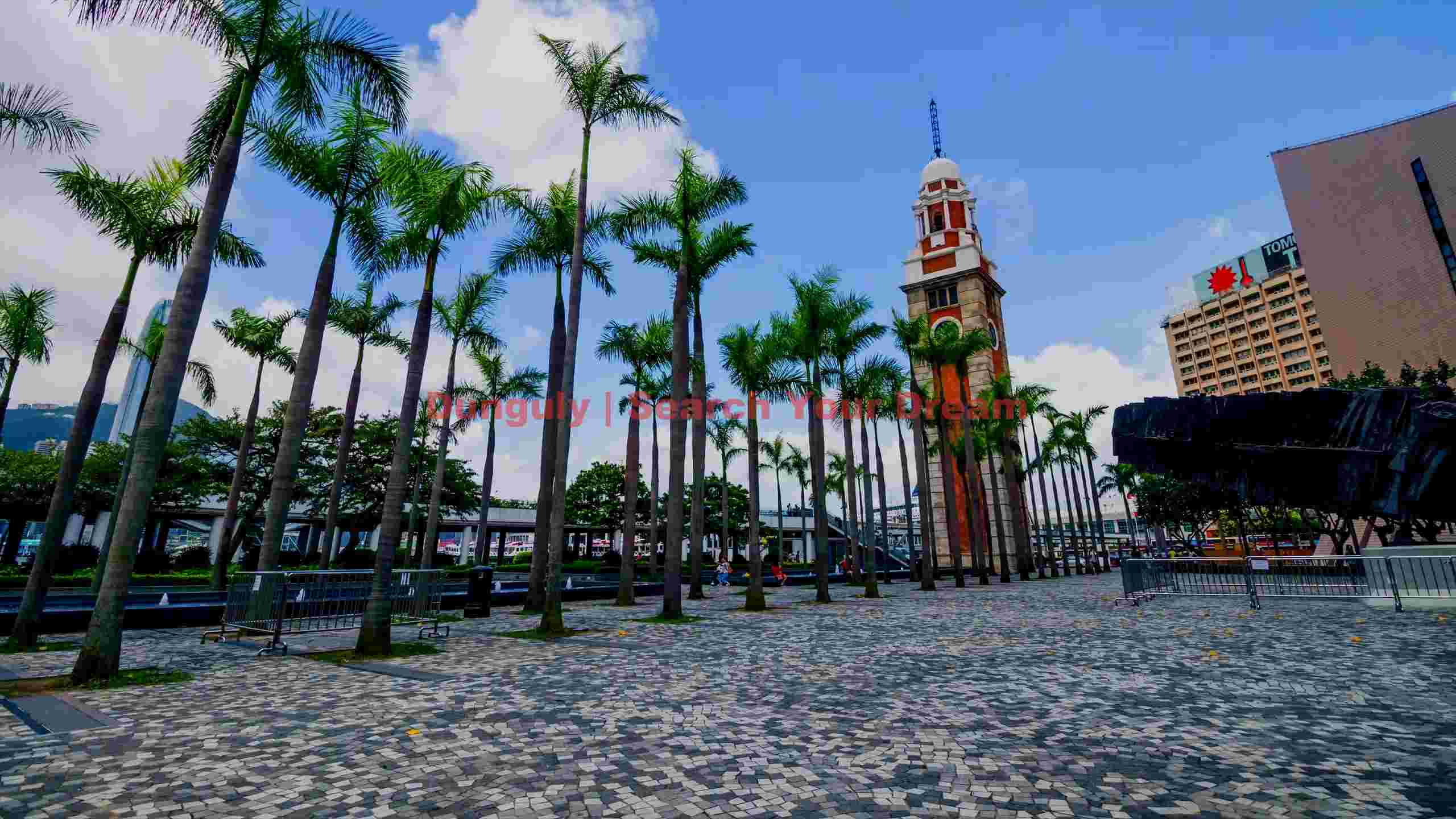 historic hong kong clock tower amidst palm trees historic hong kong clock tower amidst palm trees