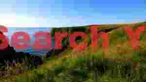 sunny green coastal cliffs overlooking azure sea