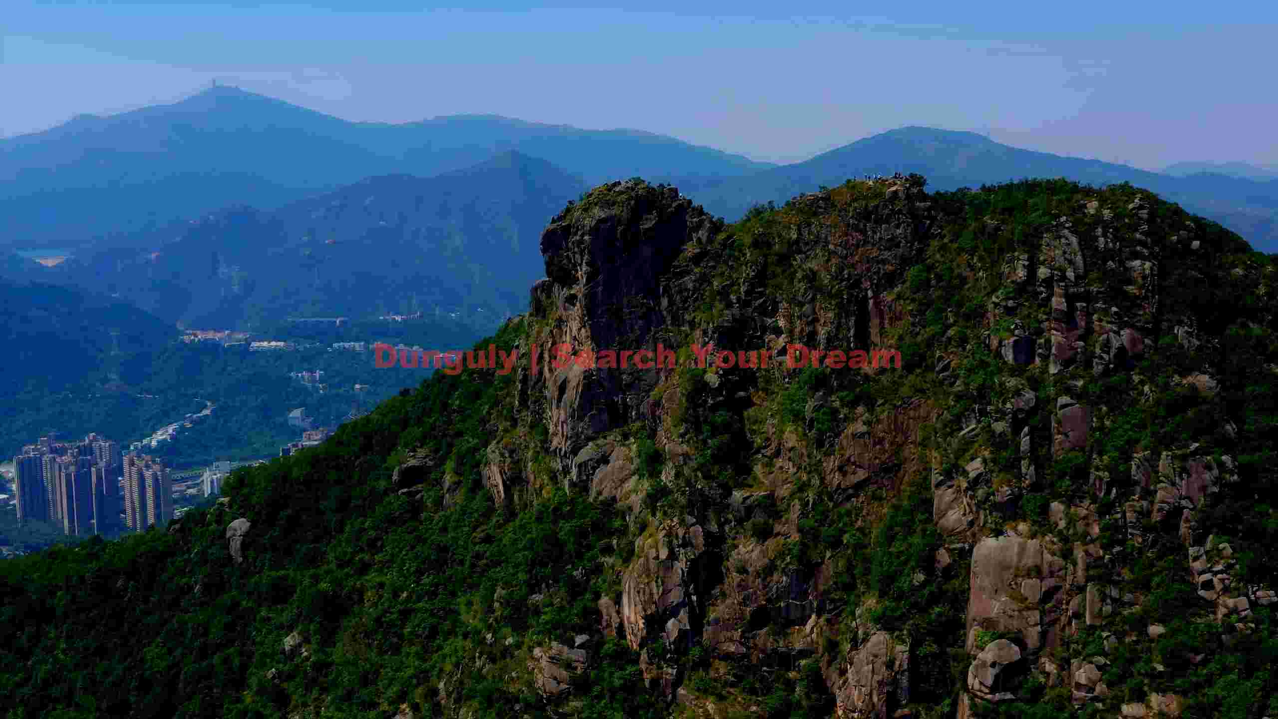 towering green mountains with distant cityscape towering green mountains with distant cityscape
