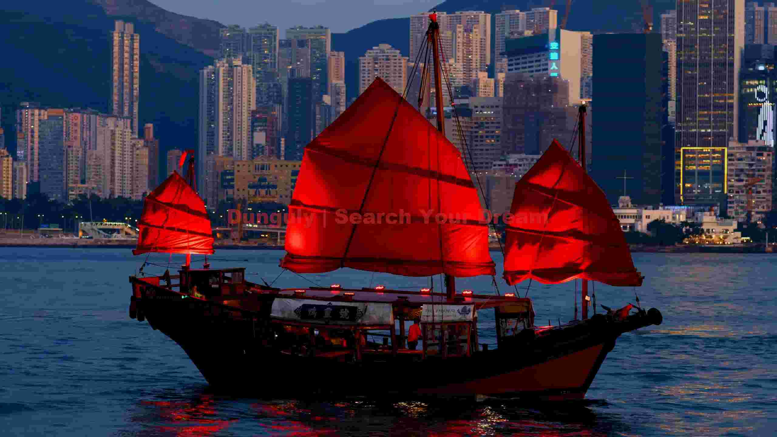 vibrant red sailed junk boat in hong kong harbor at dusk vibrant red sailed junk boat in hong kong harbor at dusk