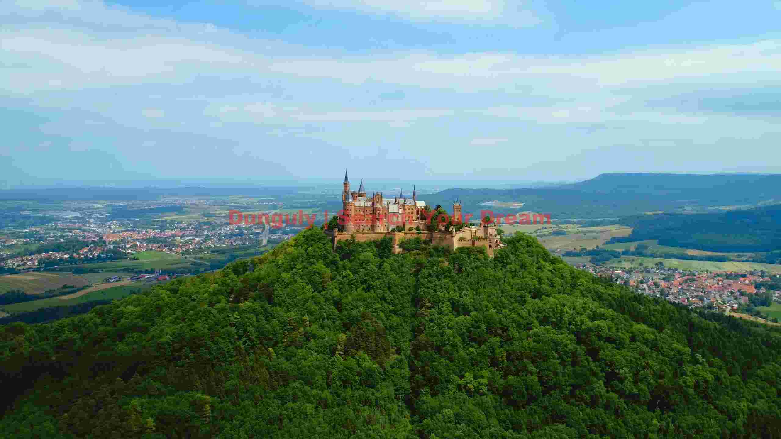 majestic hohenzollern castle amidst lush green hills majestic hohenzollern castle amidst lush green hills